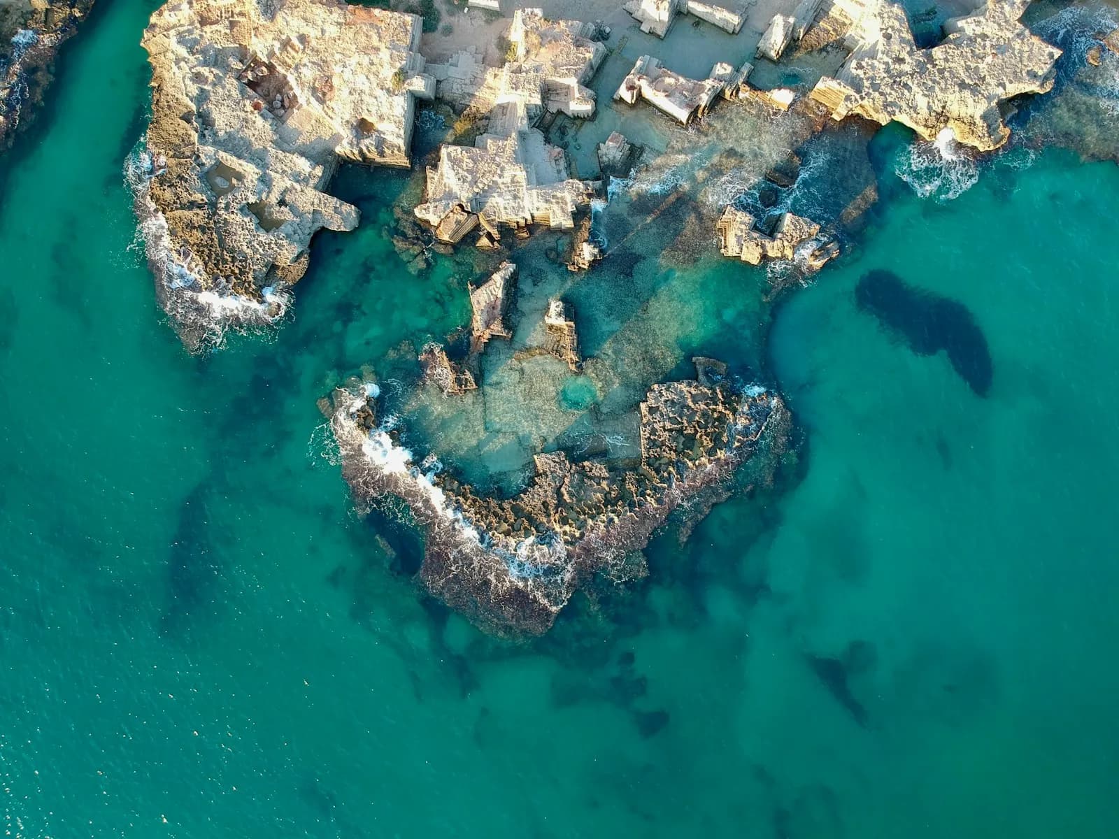 Isolotto roccioso con acque turchesi lungo la costa italiana, vista aerea dal mare