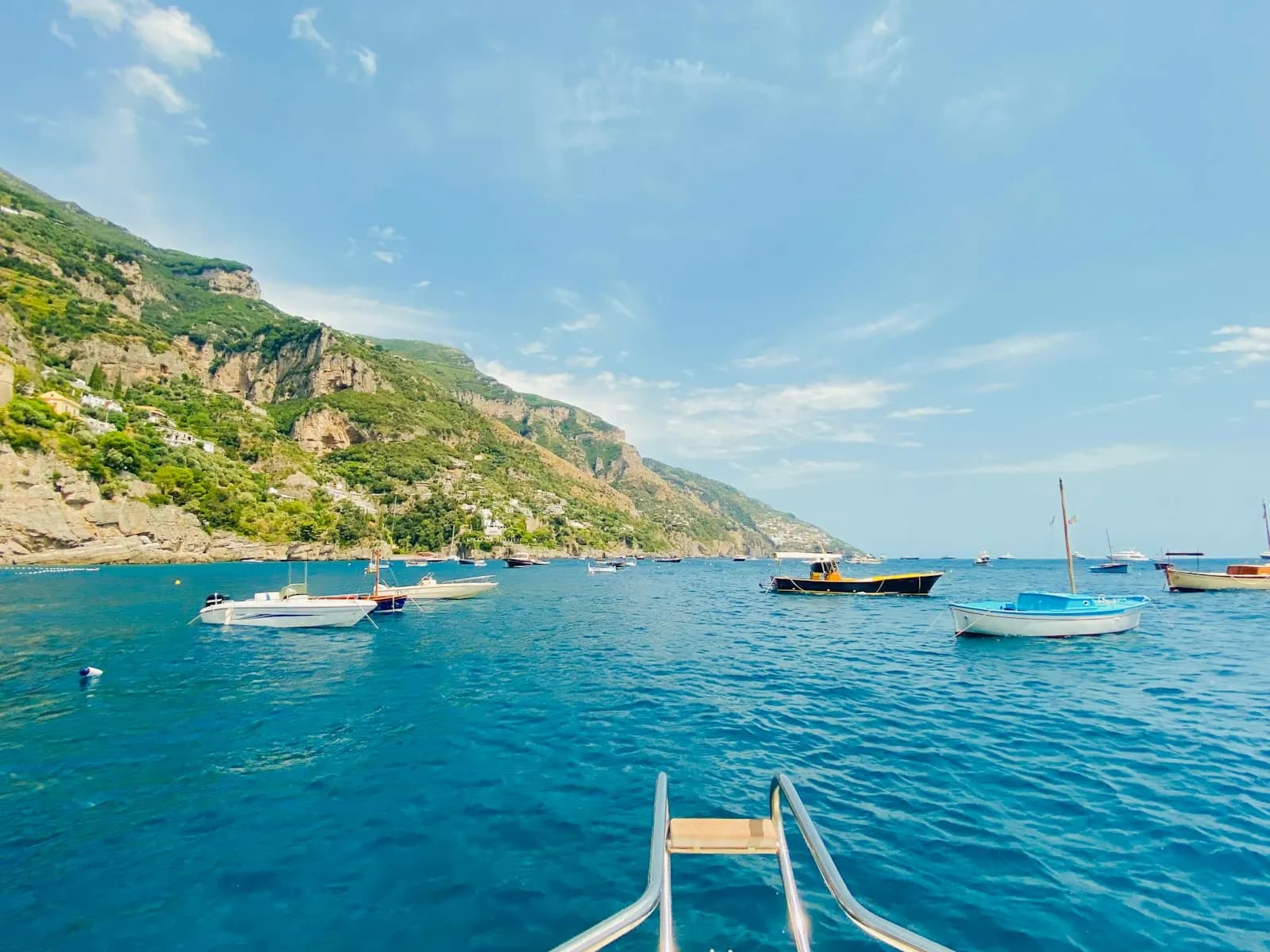 Piccole barche a motore ancorate lungo la costa della Campania, viste dal mare