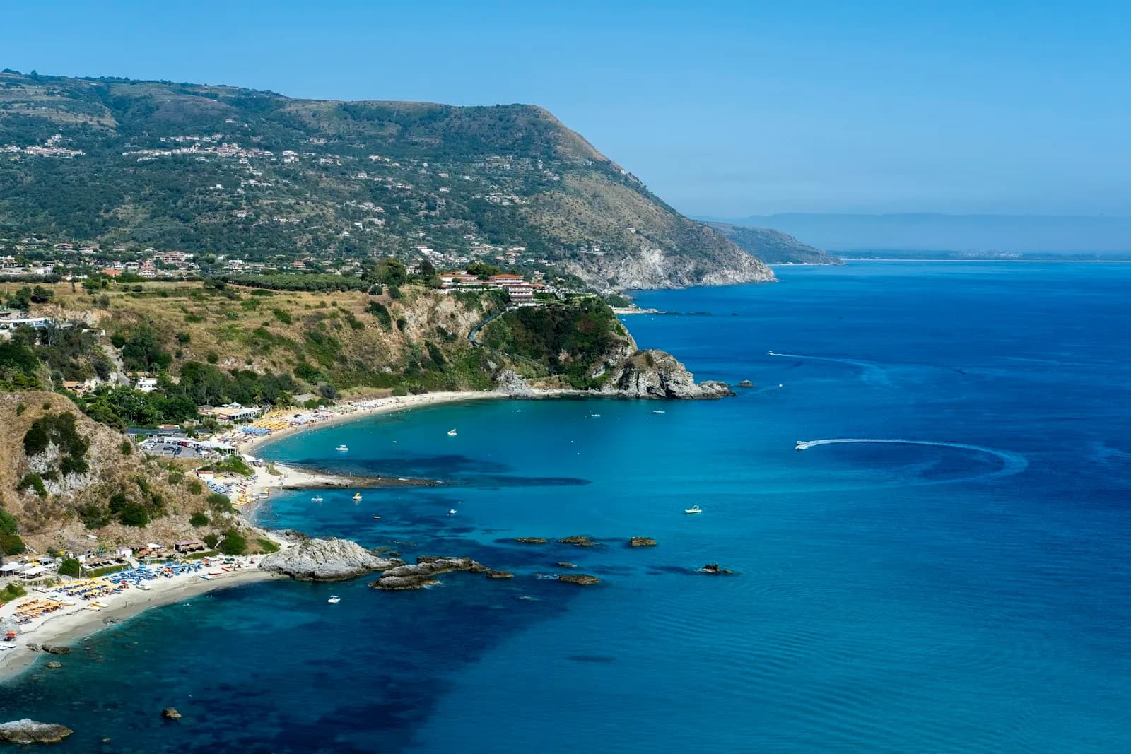 Una baia della Costa degli Dei vista dal mare, con una barca all'ancora