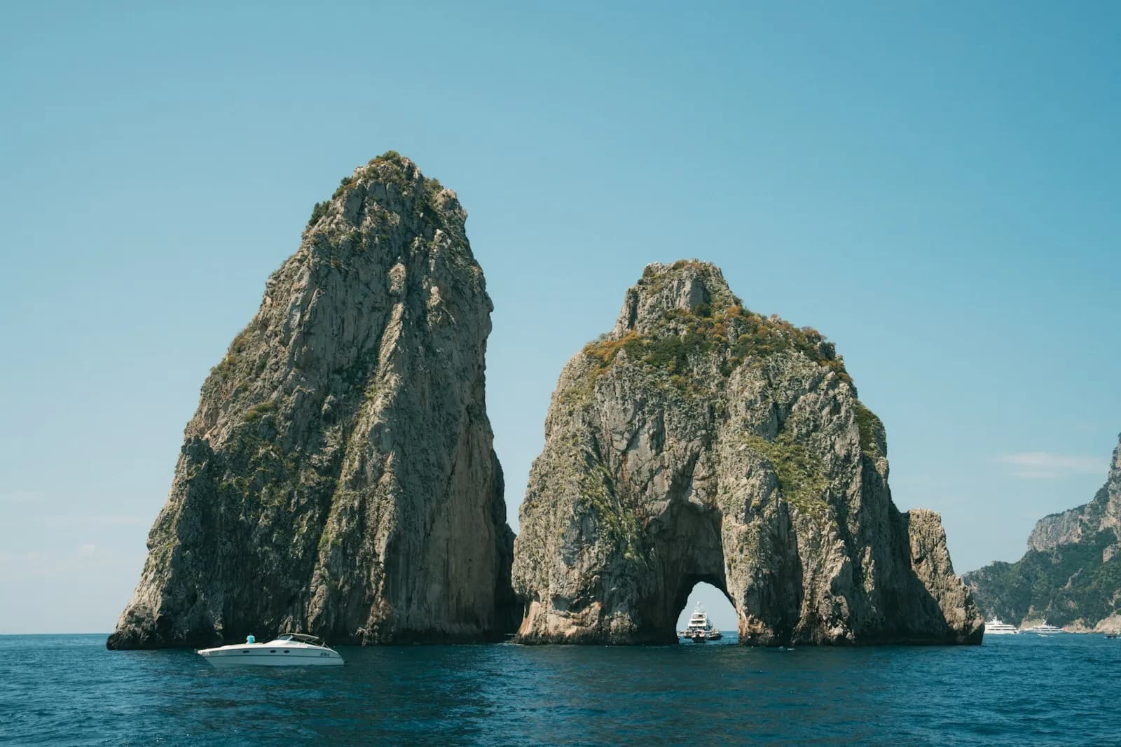 I Faraglioni di Capri visti dal mare con una barca in navigazione