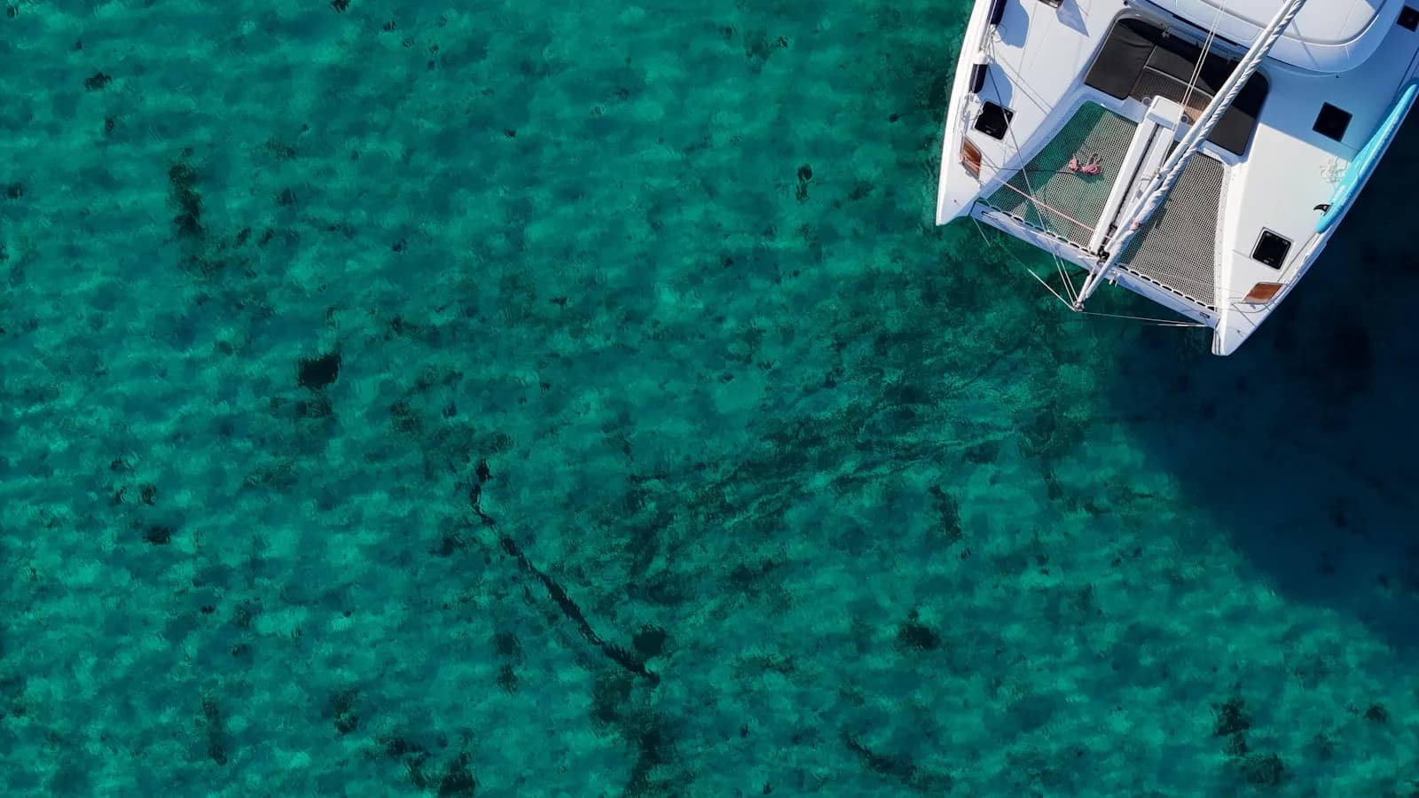 Veduta dall'alto di un catamarano bianco su acqua turchese del Mediterraneo
