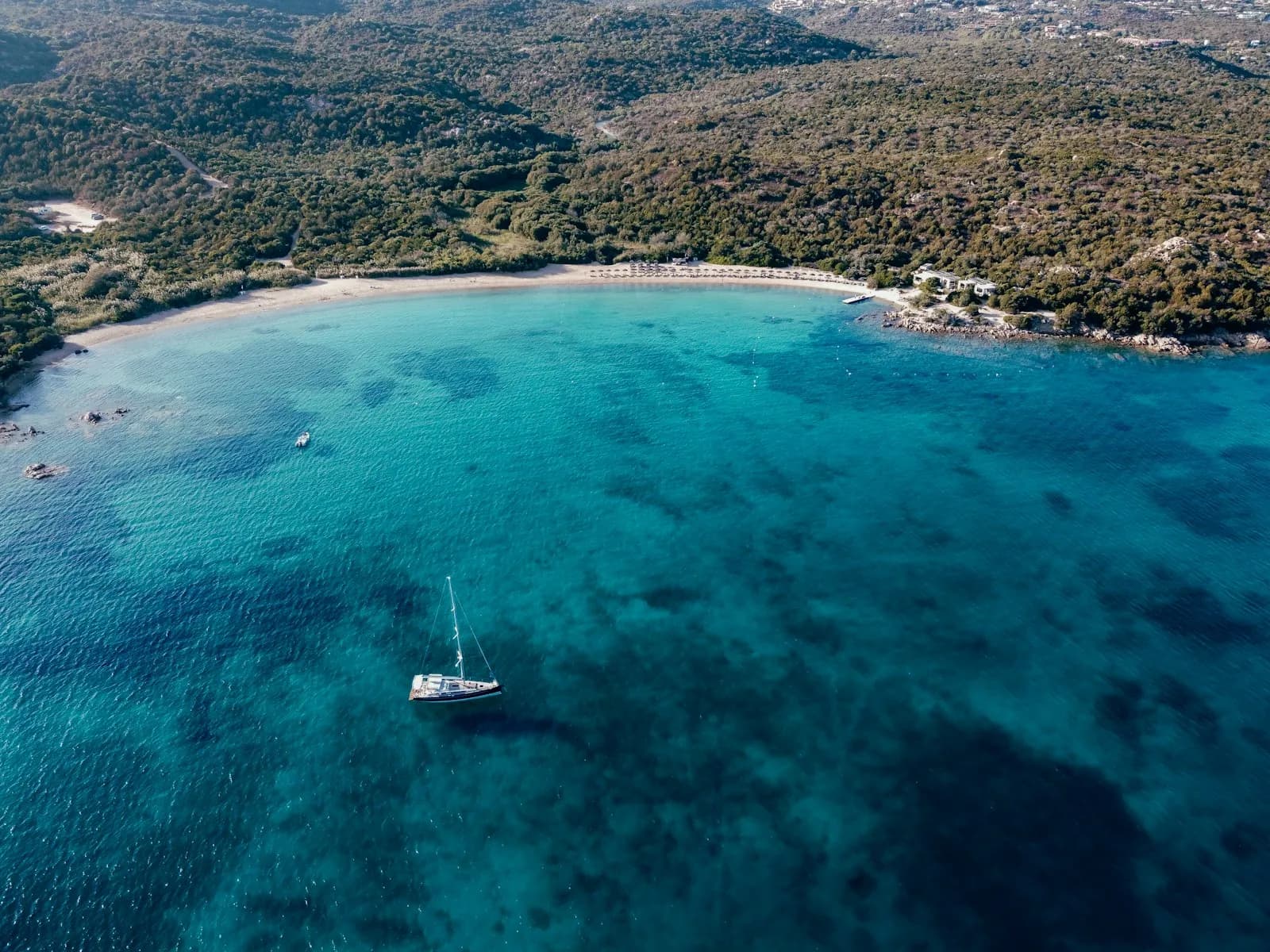 Veduta aerea di una barca in una cala dall'acqua turchese della Costa Smeralda