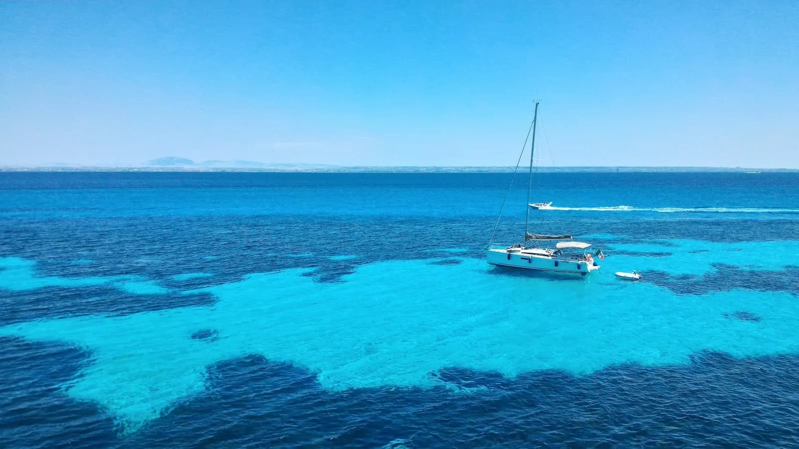 Acque turchesi con barche all'ancora lungo la costa di Favignana, isole Egadi