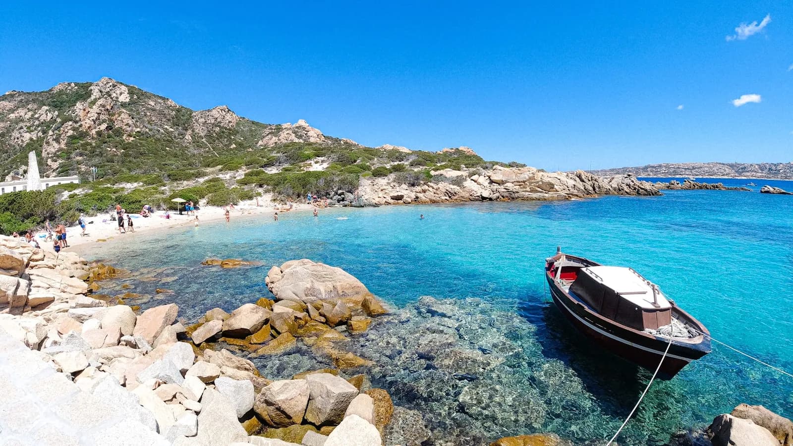 Una barca all'ancora in acque turchesi tra le rocce di granito della Gallura, Sardegna