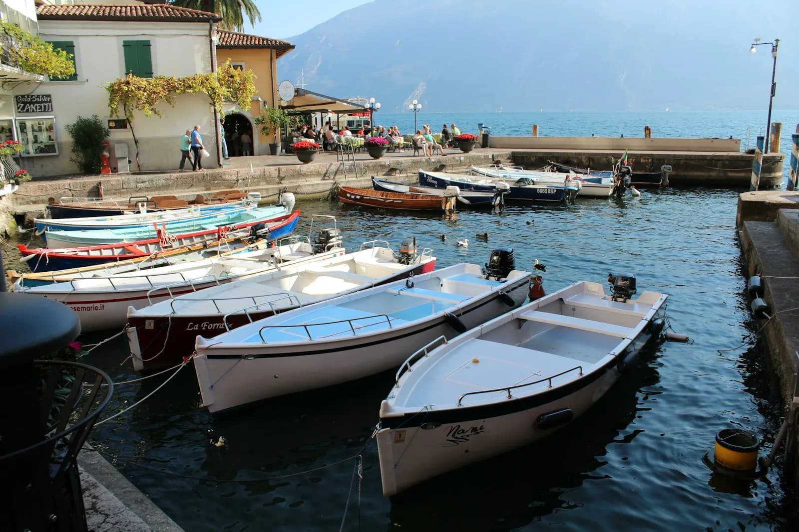 Una piccola barca a motore bianca e blu ormeggiata sul Lago di Garda a Limone