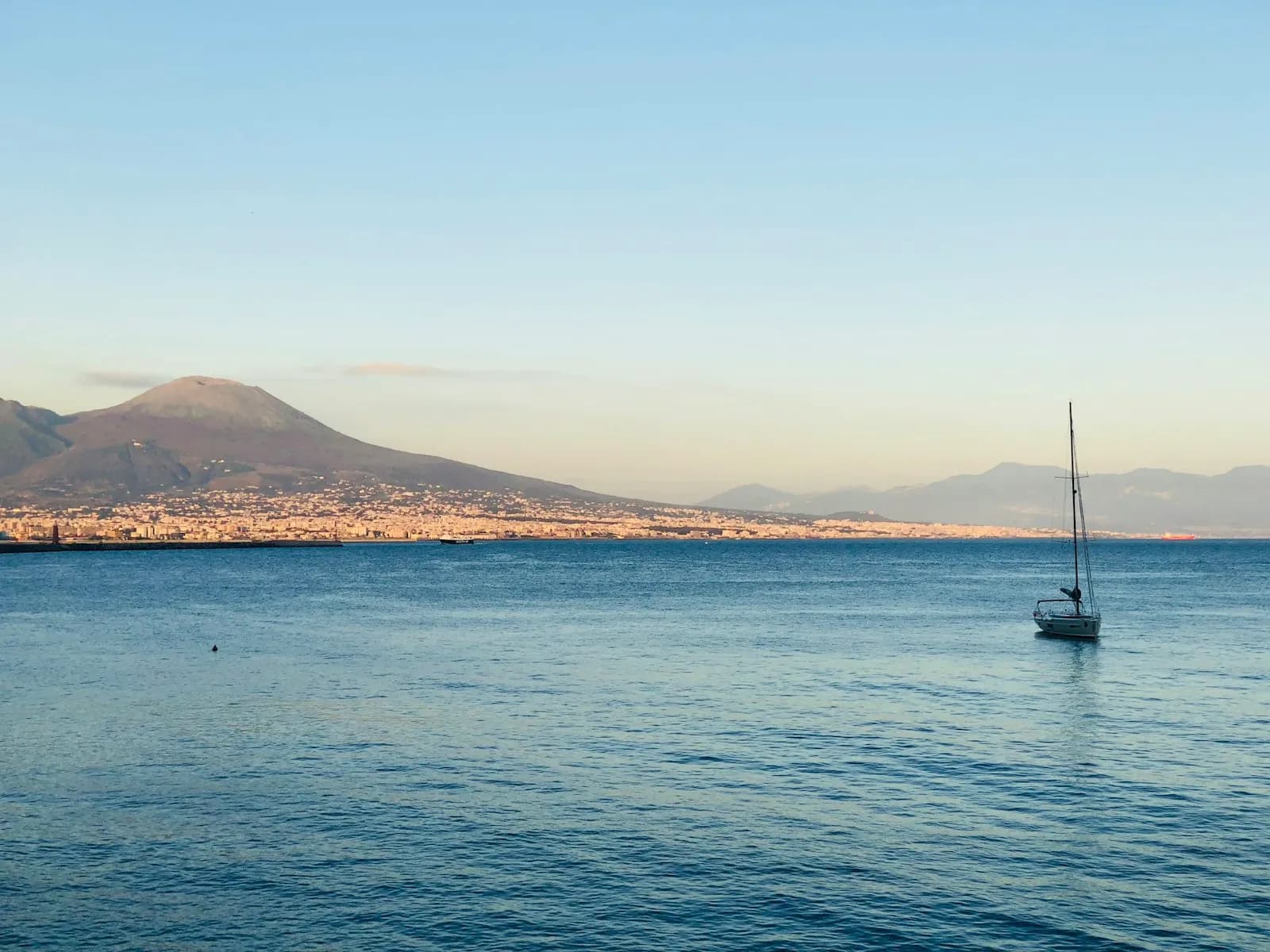 Barca a vela ancorata nel Golfo di Napoli al tramonto con il Vesuvio sullo sfondo