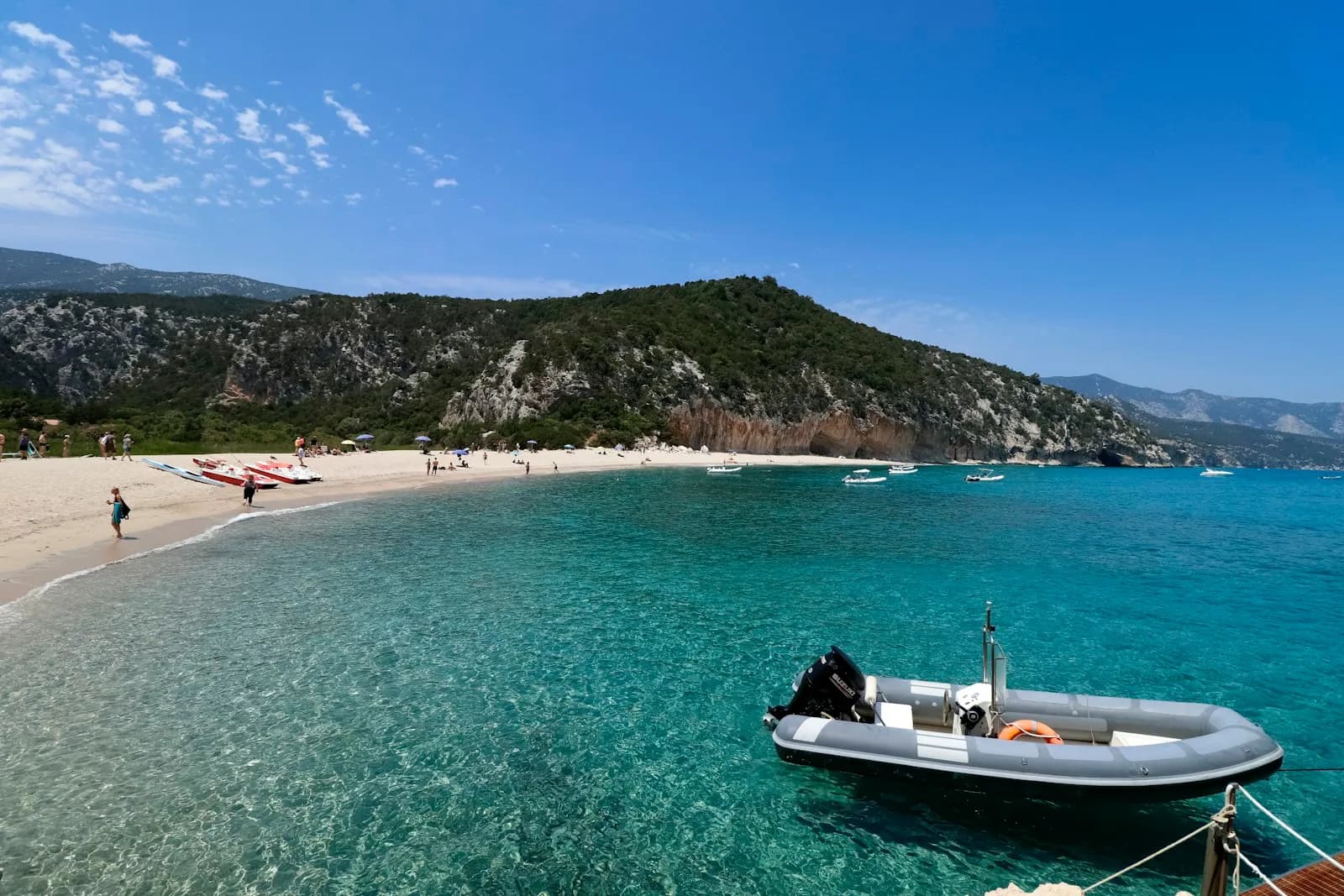 Gommone ormeggiato in una piccola baia con acqua turchese e spiaggia