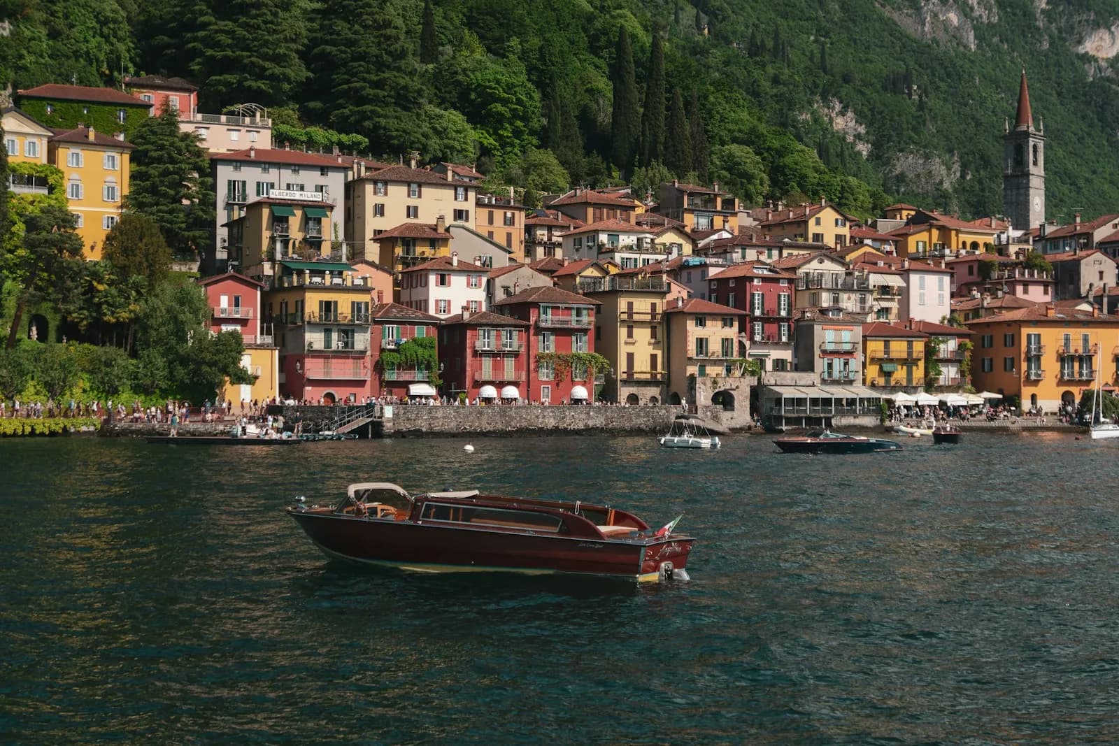 Barca in legno sul Lago di Como davanti al borgo colorato di Varenna