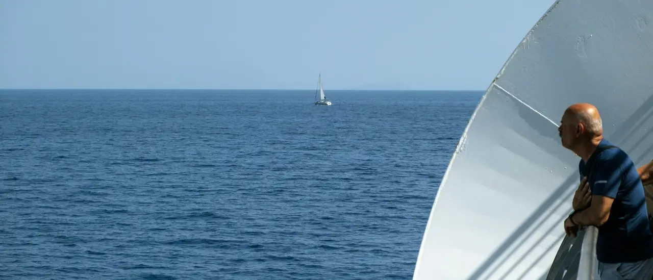 Passeggero guarda l'orizzonte dal parapetto di una nave nel mare calmo