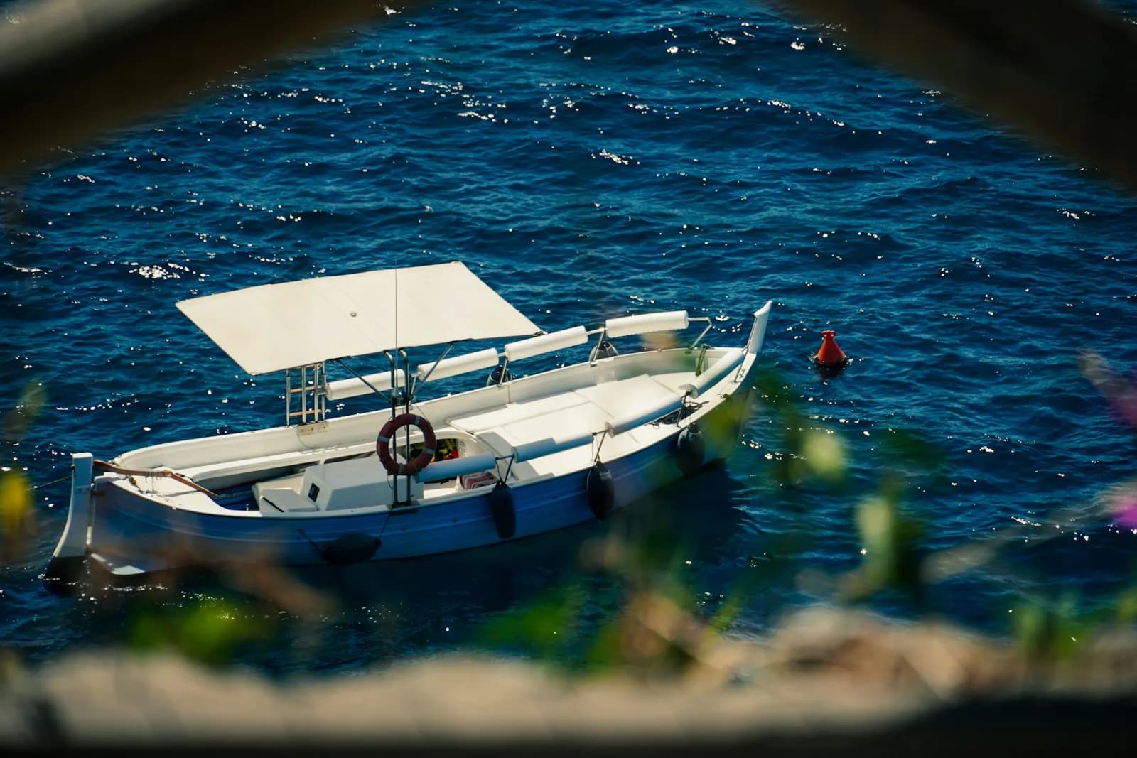 Piccola barca bianca ormeggiata su acqua blu lungo la costa italiana