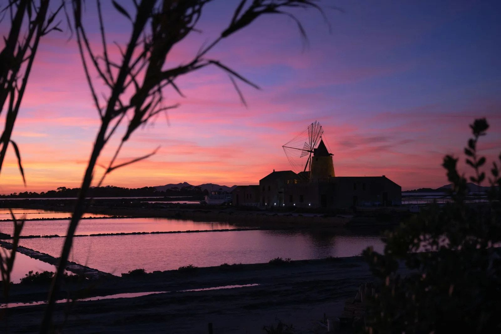Un mulino a vento delle saline dello Stagnone di Marsala stagliato contro il cielo al tramonto