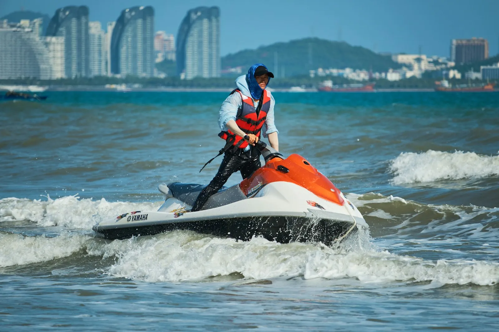 Moto d'acqua in navigazione veloce su mare azzurro sotto costa