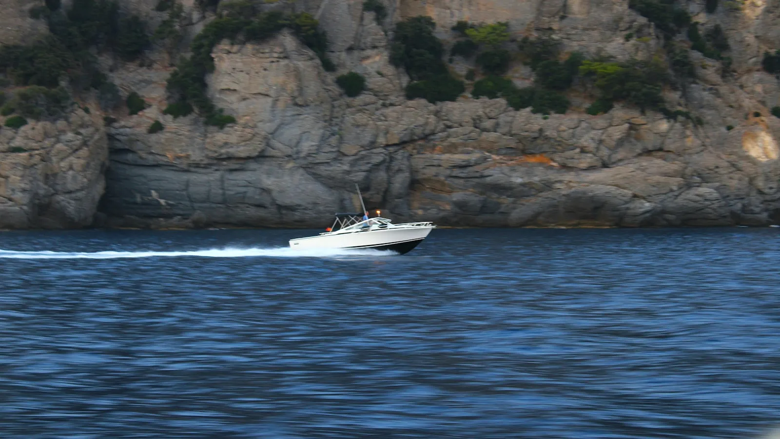 Motoscafo in navigazione al largo di una scogliera