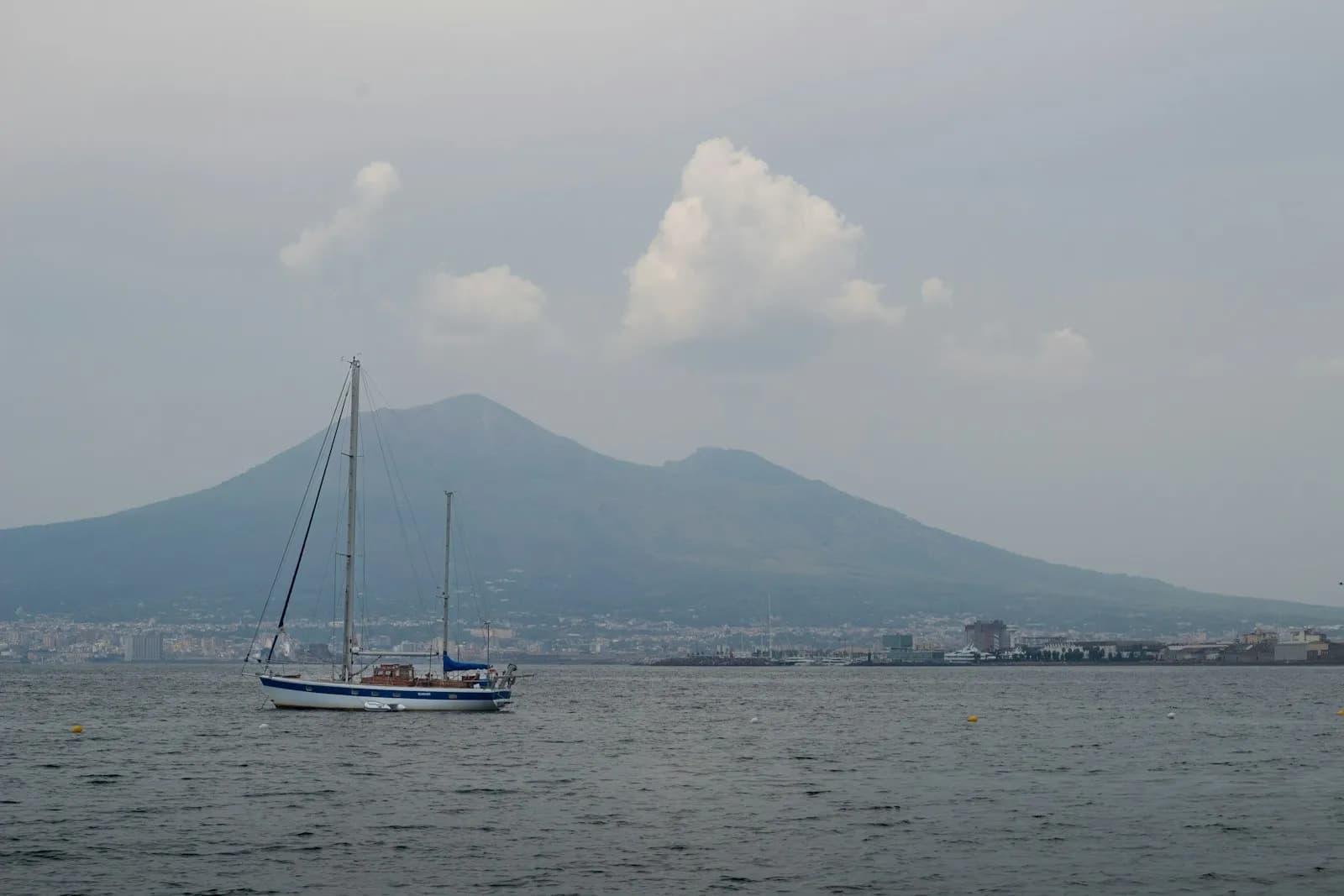 Una barca a vela naviga nel golfo di Napoli con il Vesuvio sullo sfondo