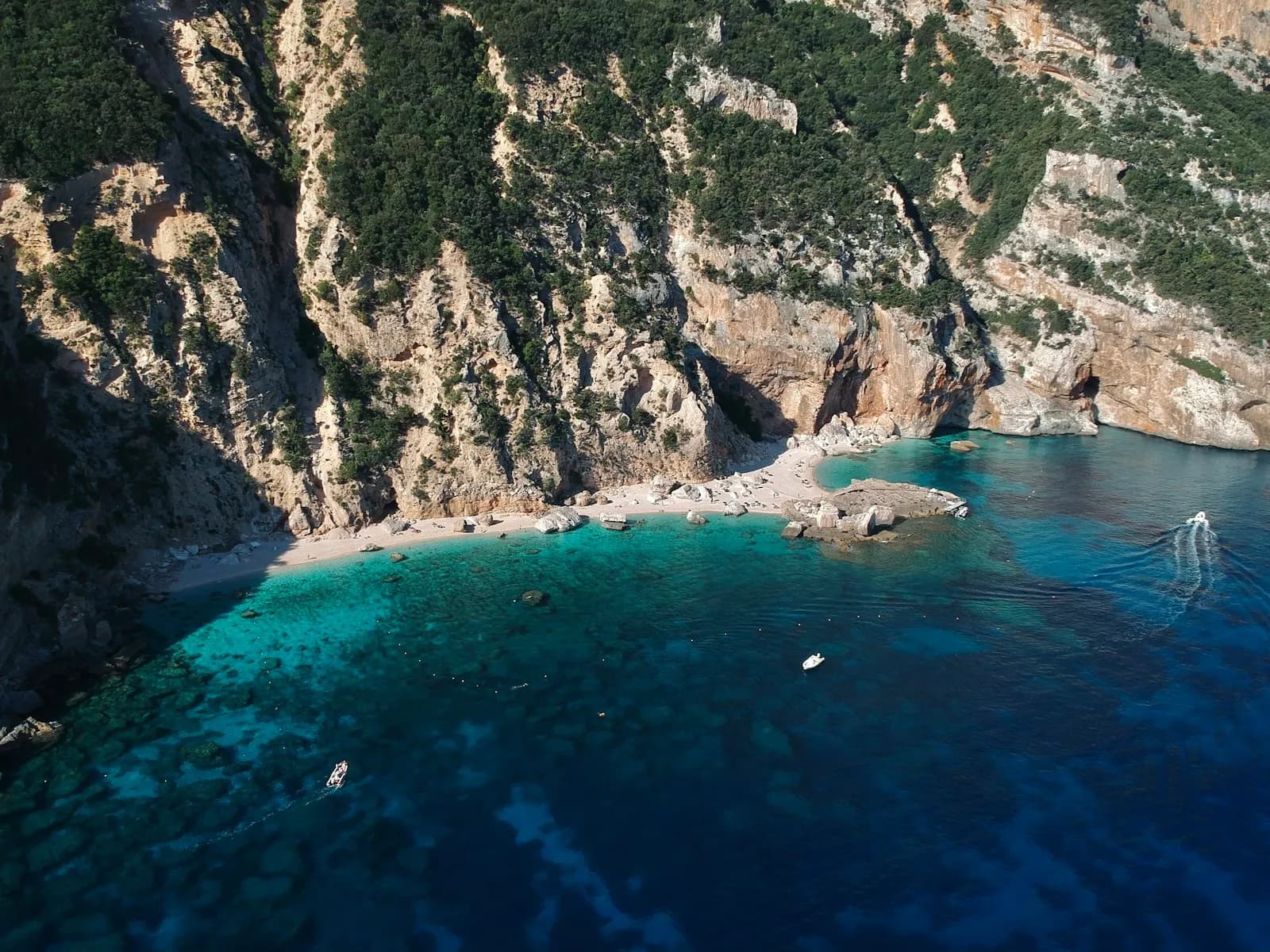 Una barca all'ancora nelle acque turchesi di una cala ai piedi di alte falesie