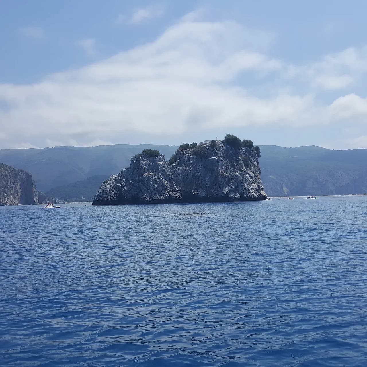 Lo scoglio roccioso di Capo Palinuro nel mare blu del Cilento, con piccole barche al largo