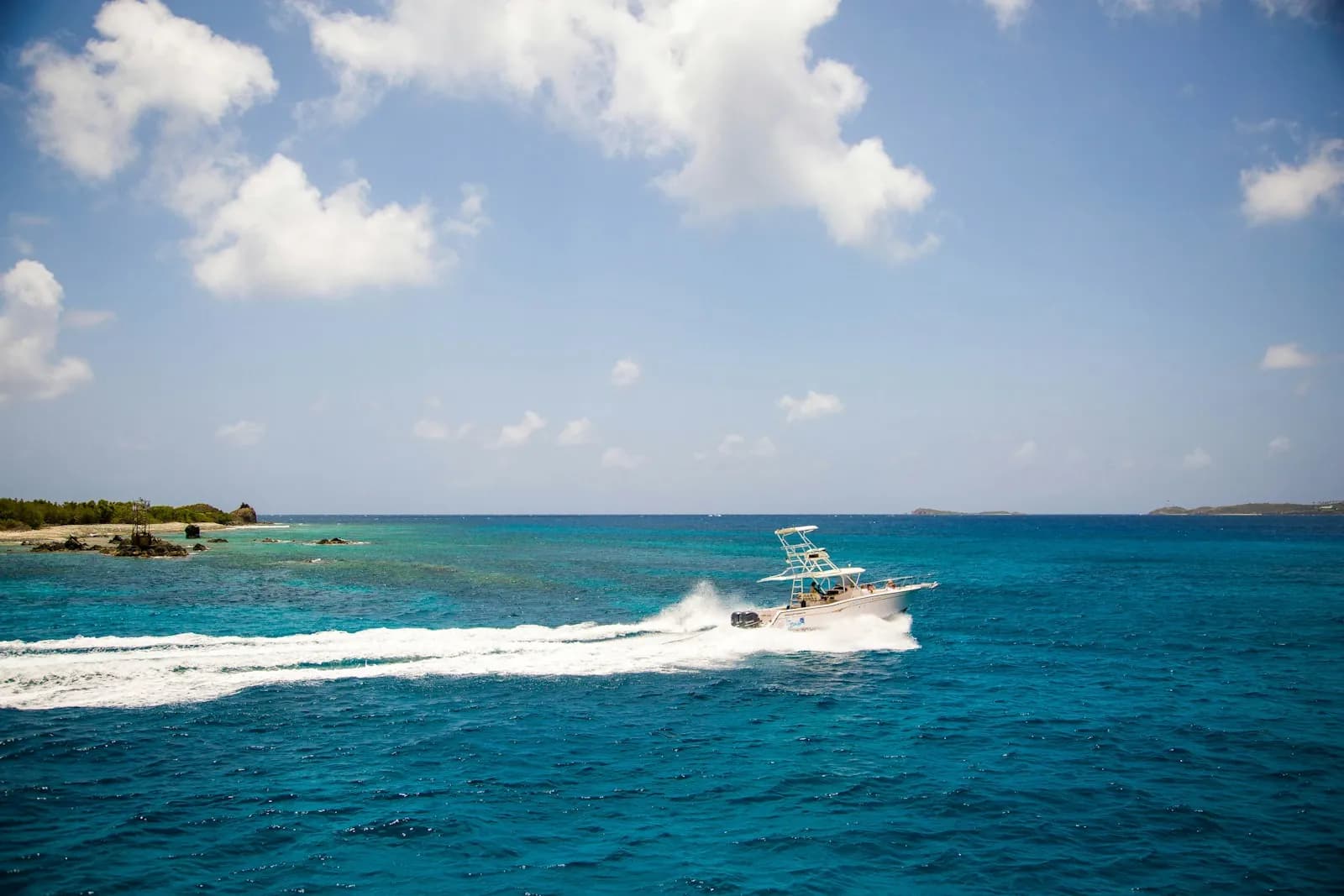 Motoscafo che naviga veloce su mare azzurro lungo la costa