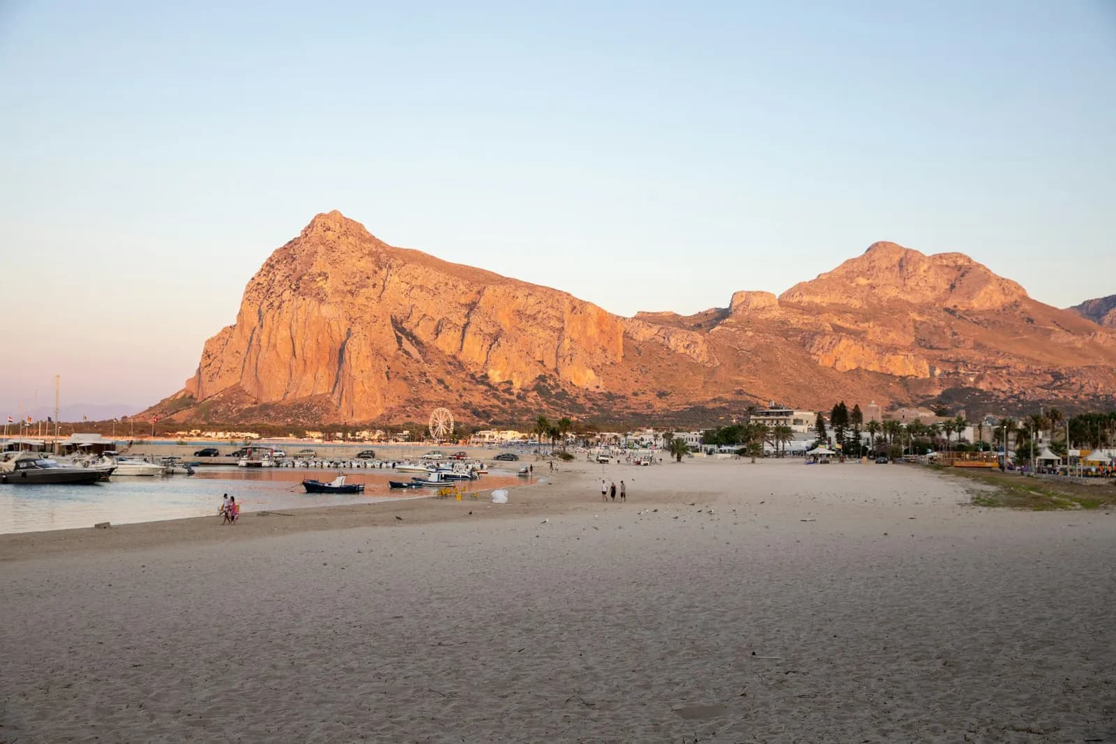 La spiaggia di San Vito Lo Capo con barche tirate a riva e il Monte Monaco sullo sfondo al tramonto
