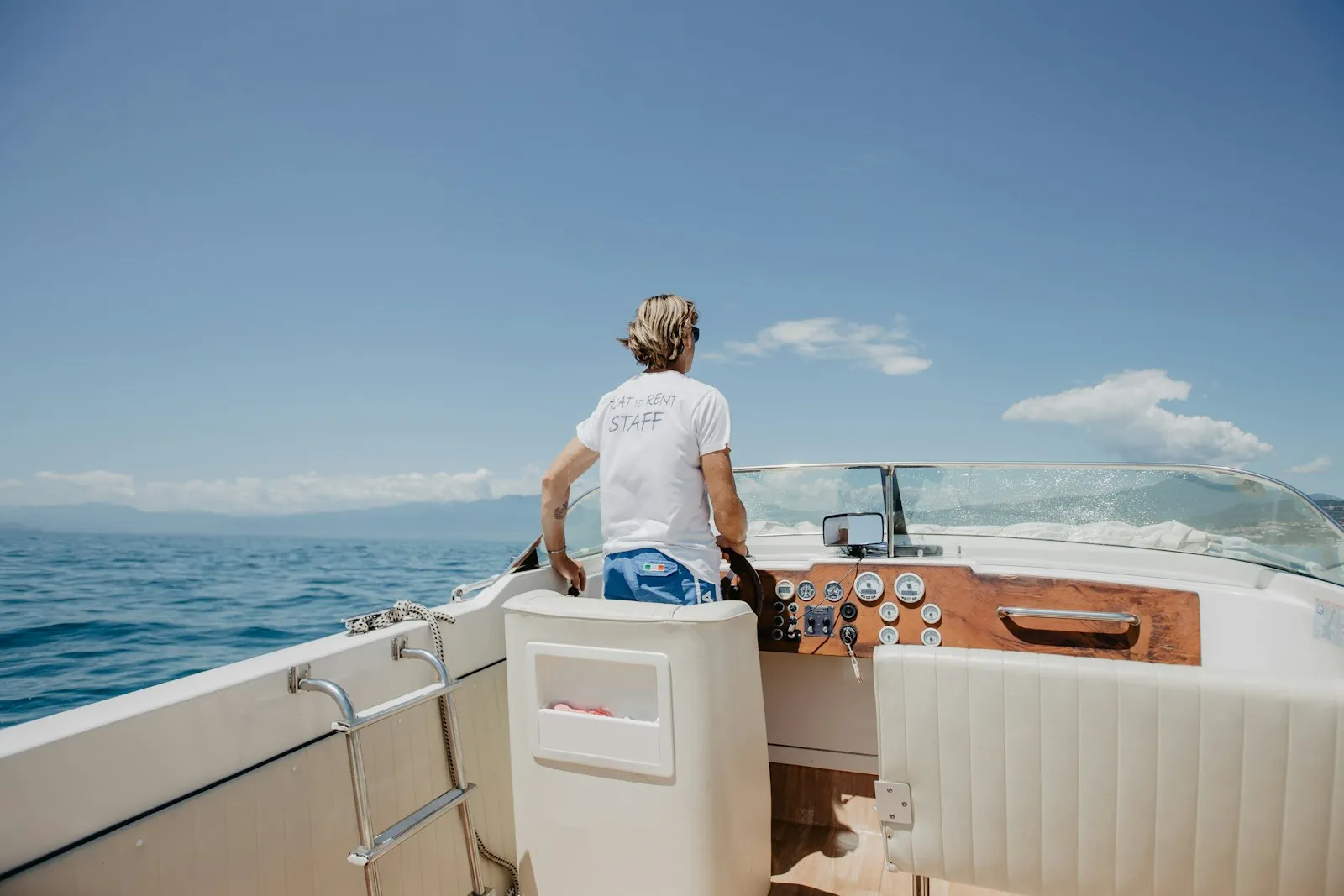 Membro dell'equipaggio in maglietta staff alla guida di una barca a motore in acque italiane