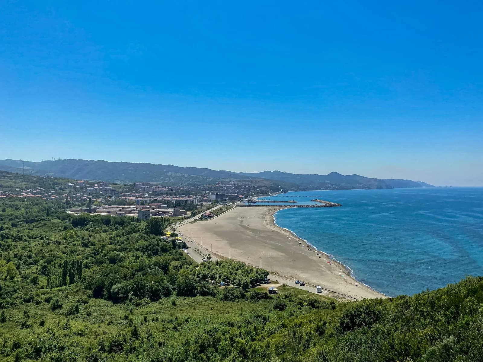 Litorale sabbioso con molo e mare turchese in una baia mediterranea