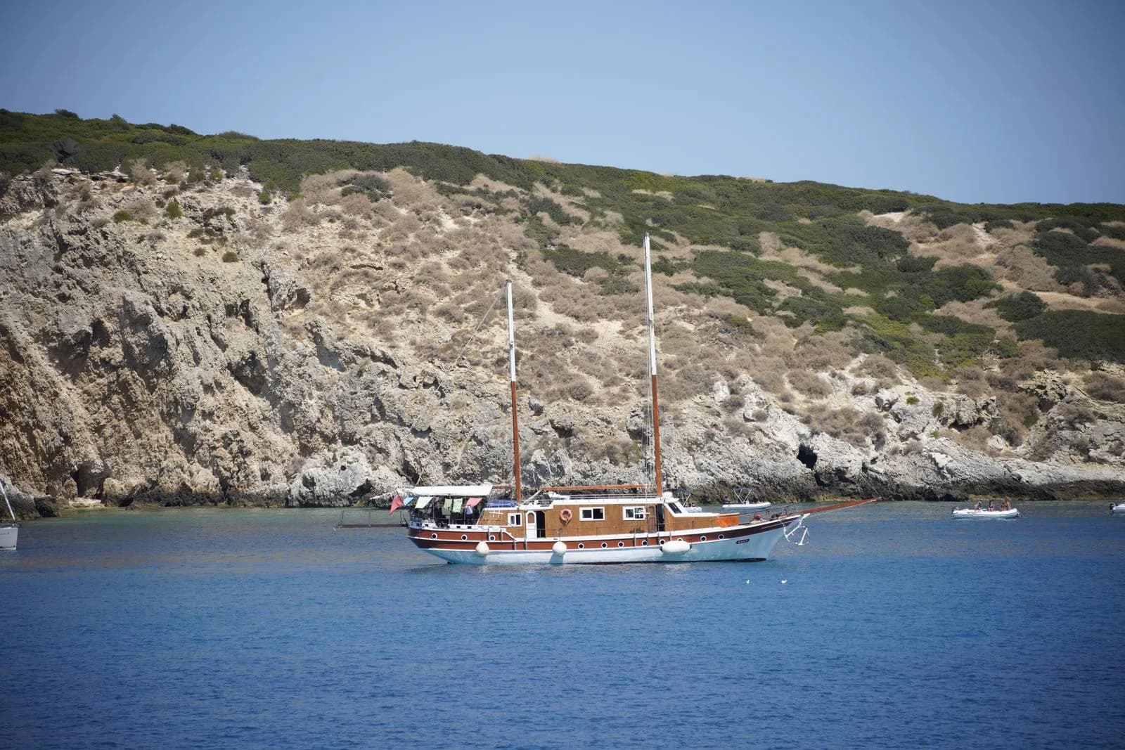 Yacht in legno all'ancora vicino alla costa rocciosa di San Nicola, Isole Tremiti