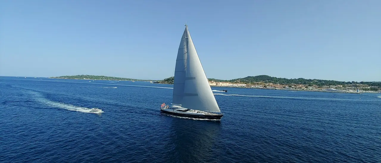 Barca a vela a vele spiegate lungo la costa in una giornata di sole