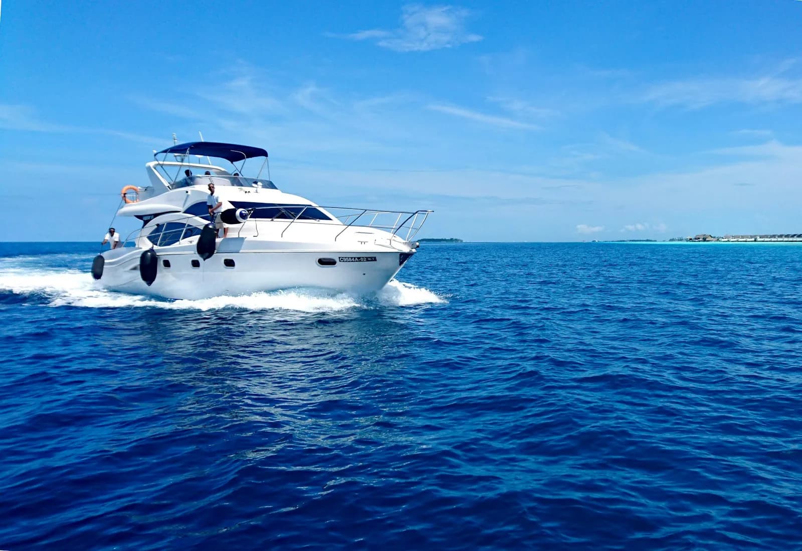 Yacht a motore bianco e blu in navigazione su mare aperto sotto un cielo sereno