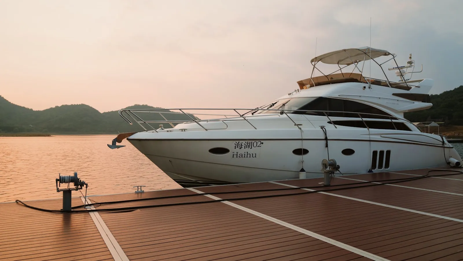 Yacht a motore bianco ormeggiato a una banchina in legno in una giornata serena