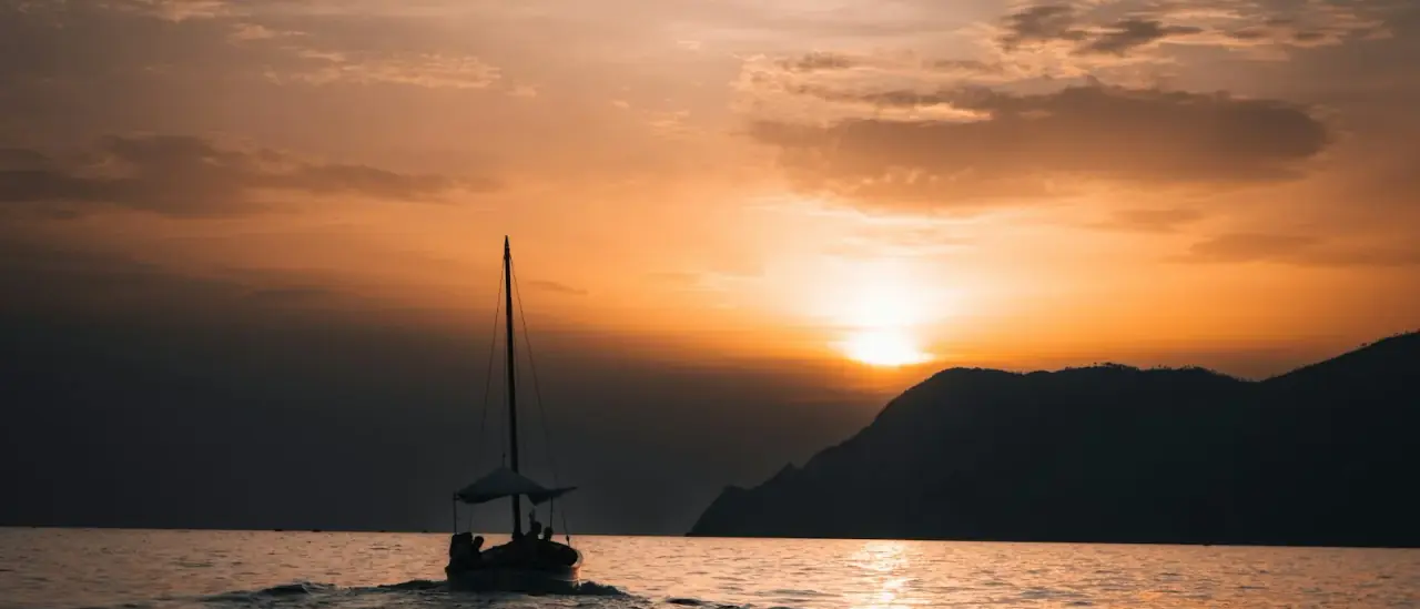 Barca a vela silhouette al tramonto in navigazione al largo