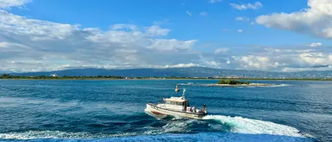 Piccola barca cabinata bianca naviga su un mare blu