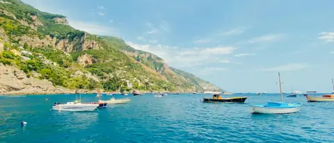 Piccole barche a motore ancorate lungo la costa della Campania, viste dal mare