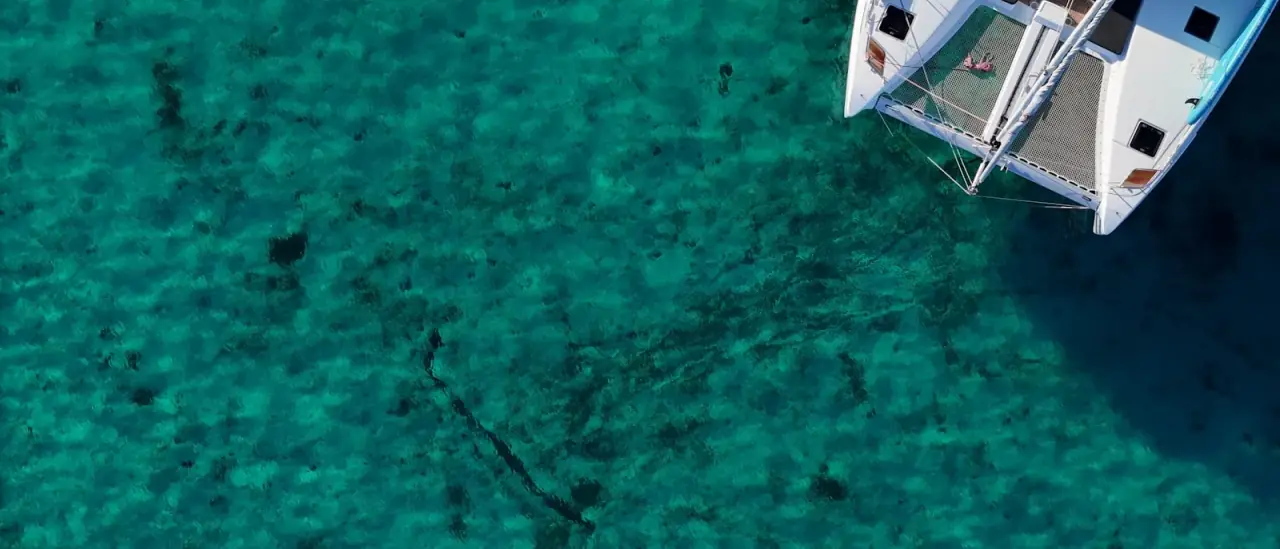 Veduta dall'alto di un catamarano bianco su acqua turchese del Mediterraneo