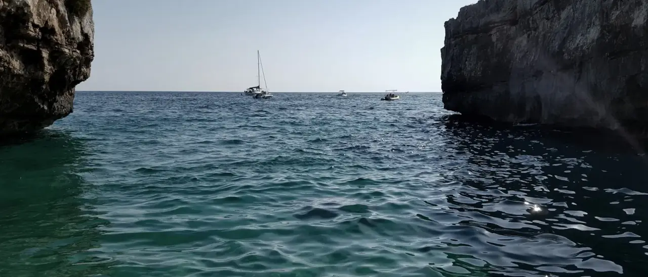 Barche da diporto lungo la costa ionica pugliese, tra insenature rocciose e acque limpide