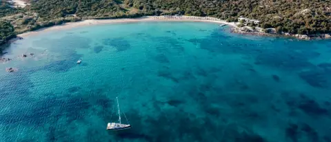 Veduta aerea di una barca in una cala dall'acqua turchese della Costa Smeralda