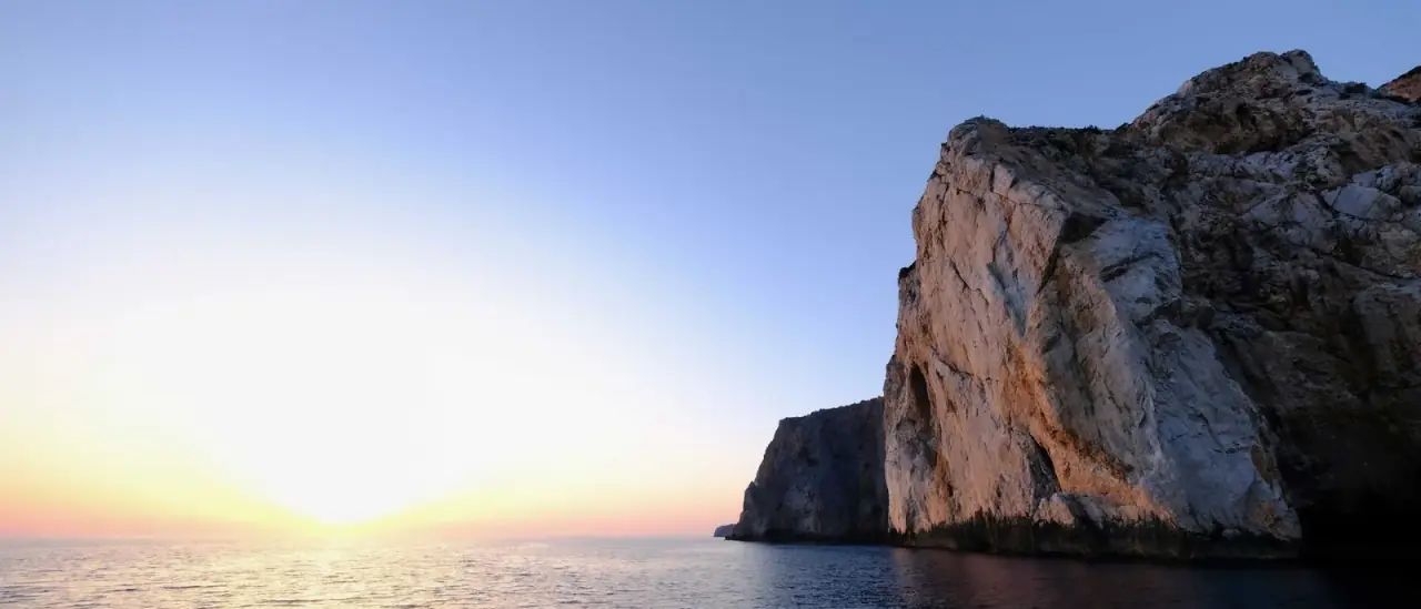 Falesia bianca a picco sul mare illuminata dai colori caldi del tramonto