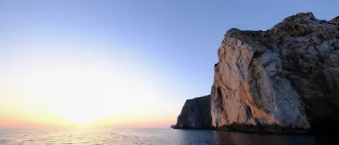Falesia bianca a picco sul mare illuminata dai colori caldi del tramonto