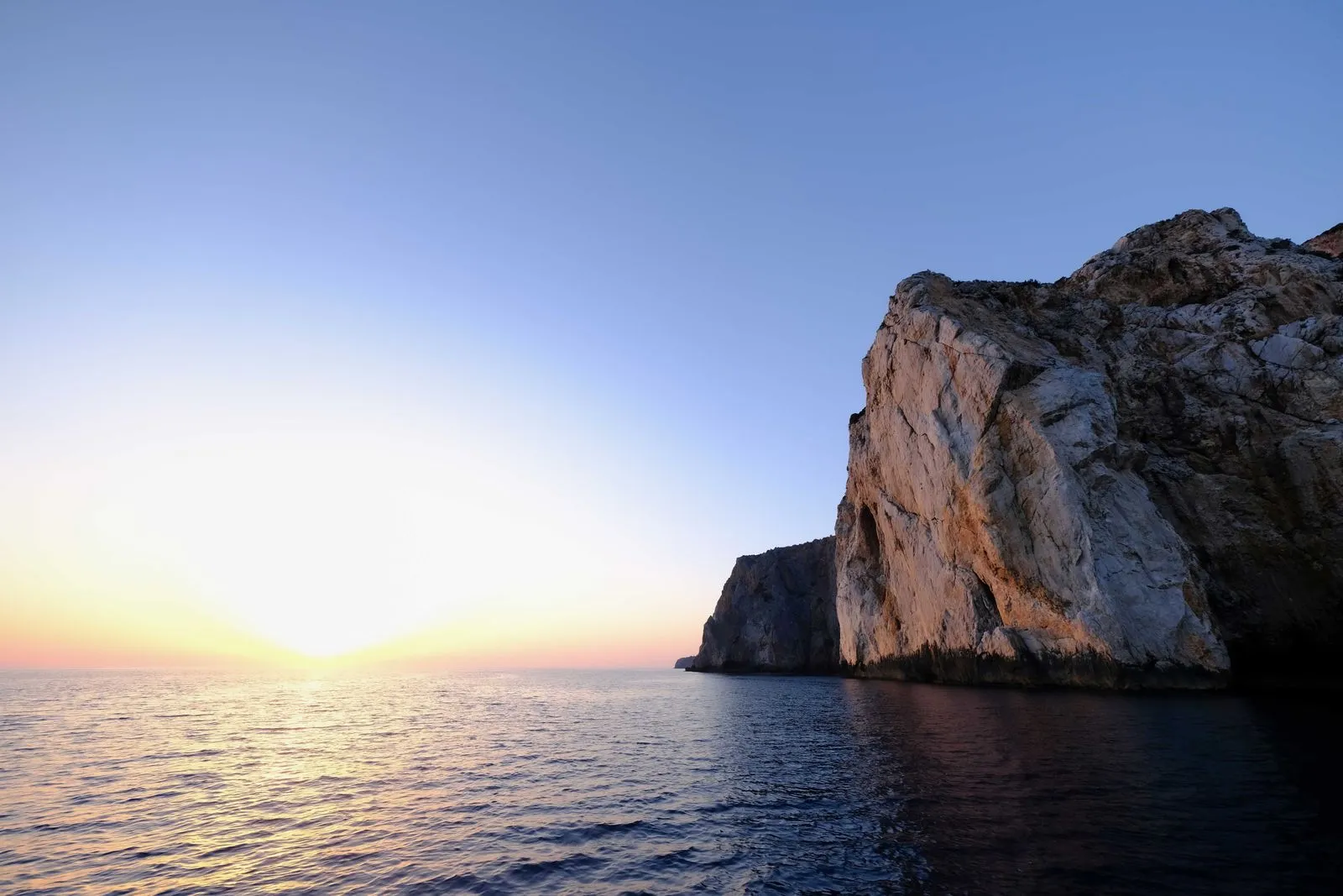 Falesia bianca a picco sul mare illuminata dai colori caldi del tramonto
