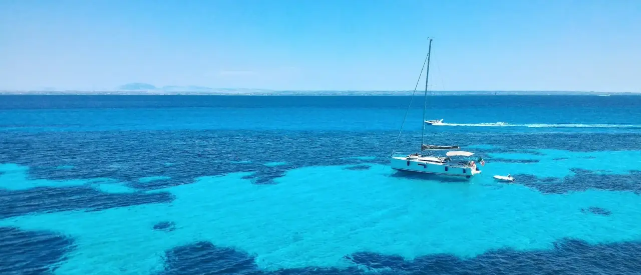 Acque turchesi con barche all'ancora lungo la costa di Favignana, isole Egadi