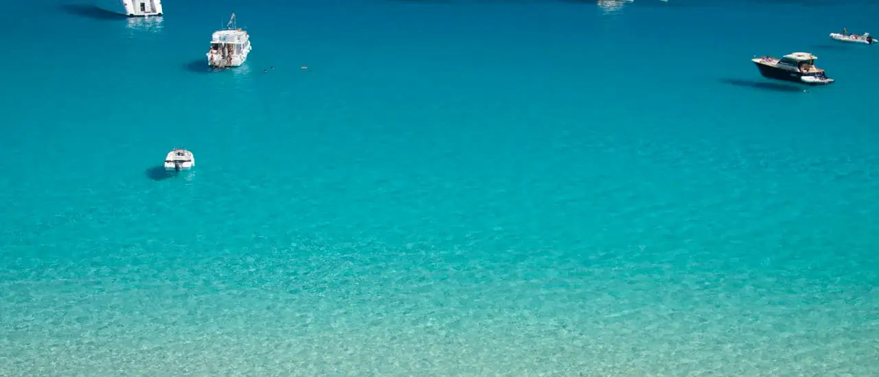 Barche all'ancora nelle acque turchesi di Cala Rossa, Favignana, isole Egadi