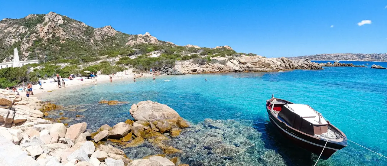 Una barca all'ancora in acque turchesi tra le rocce di granito della Gallura, Sardegna