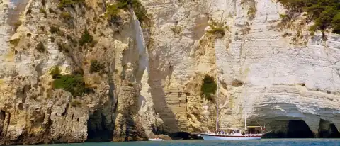 Barca da escursione sotto le falesie calcaree della costa del Gargano