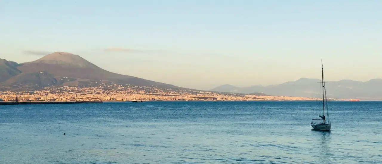 Barca a vela ancorata nel Golfo di Napoli al tramonto con il Vesuvio sullo sfondo