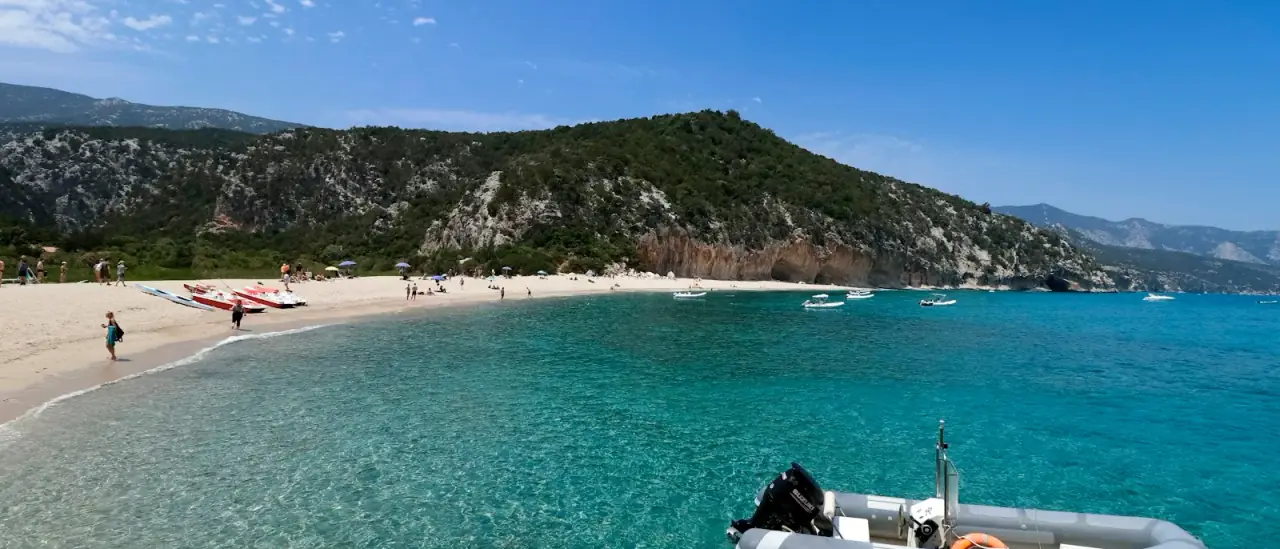 Gommone ormeggiato in una piccola baia con acqua turchese e spiaggia