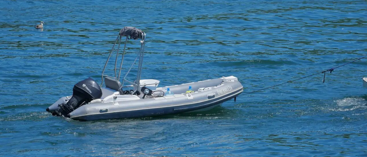 Gommone semirigido all'ancora, con tubolari e motore fuoribordo in evidenza