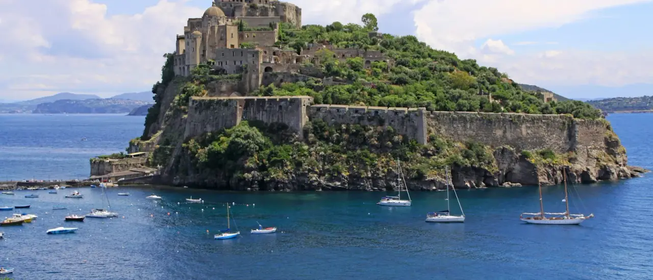 Il Castello Aragonese di Ischia con alcune barche nel mare azzurro