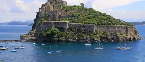 Il Castello Aragonese di Ischia con alcune barche nel mare azzurro