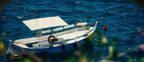Piccola barca bianca ormeggiata su acqua blu lungo la costa italiana