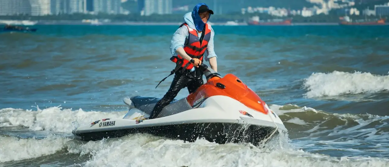 Moto d'acqua in navigazione veloce su mare azzurro sotto costa