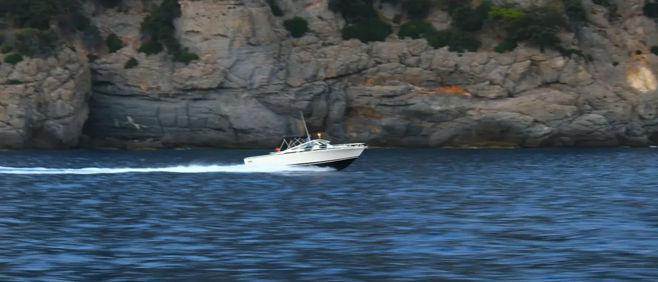 Motoscafo in navigazione al largo di una scogliera