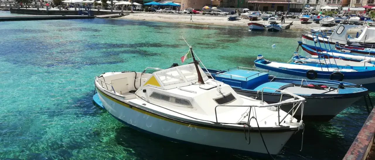 Barche ormeggiate in acque turchesi lungo la costa di Palermo, Sicilia